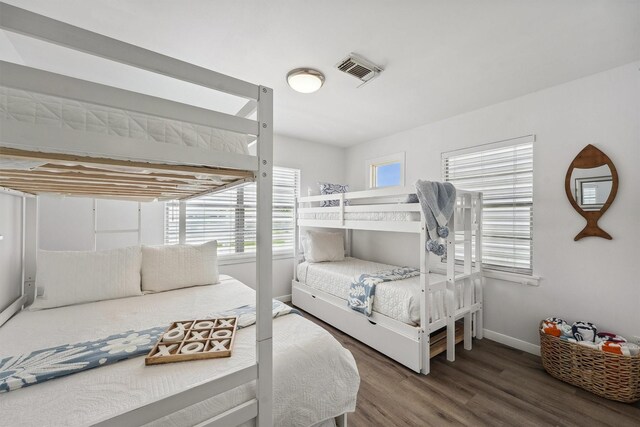 bedroom with baseboards, wood finished floors, and visible vents