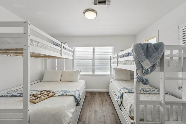 bedroom featuring baseboards, wood finished floors, and visible vents