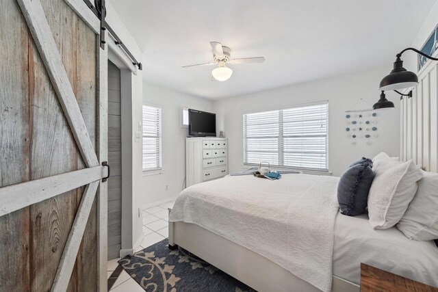 tiled bedroom with a barn door and ceiling fan