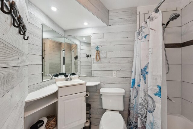 bathroom featuring shower / tub combo with curtain, wood walls, vanity, and toilet
