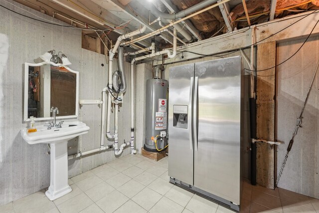 utility room featuring gas water heater and a sink