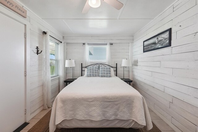 bedroom featuring wood walls and ceiling fan