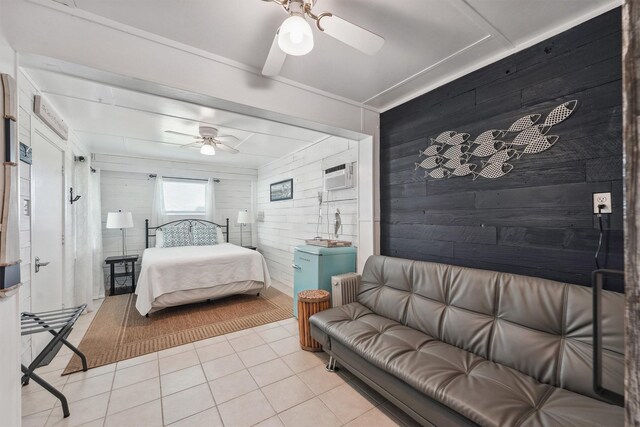 bedroom with radiator heating unit, wood walls, ceiling fan, and light tile patterned floors
