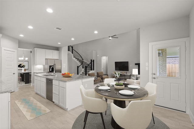 kitchen with white cabinets, stainless steel appliances, an island with sink, and light stone countertops