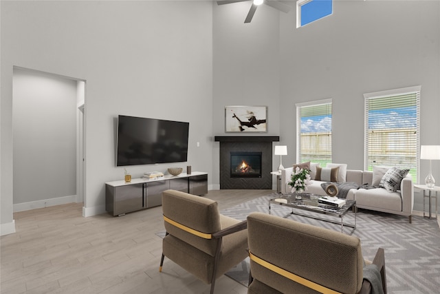 living room featuring light wood-type flooring, ceiling fan, and a high ceiling