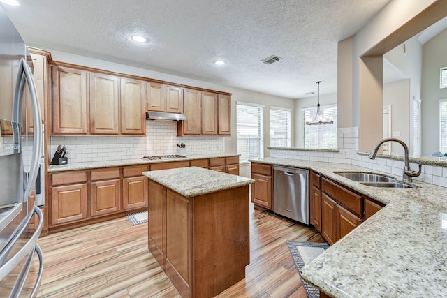 kitchen with light stone countertops, sink, a textured ceiling, stainless steel appliances, and pendant lighting