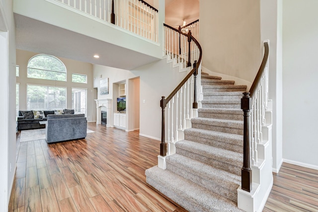 stairs featuring hardwood / wood-style flooring and a towering ceiling