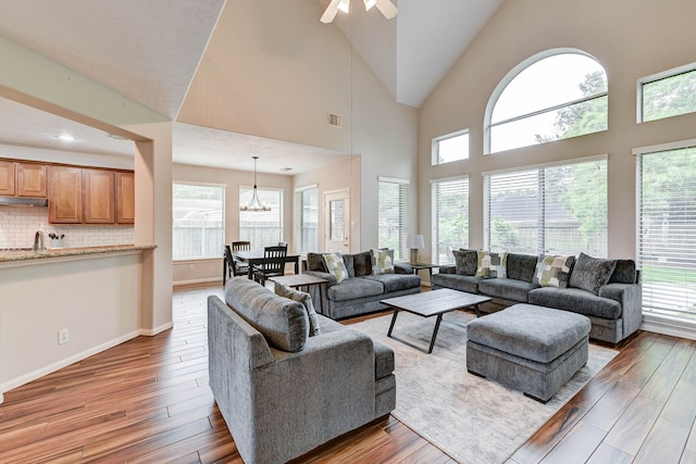 living room with high vaulted ceiling, a healthy amount of sunlight, and hardwood / wood-style flooring