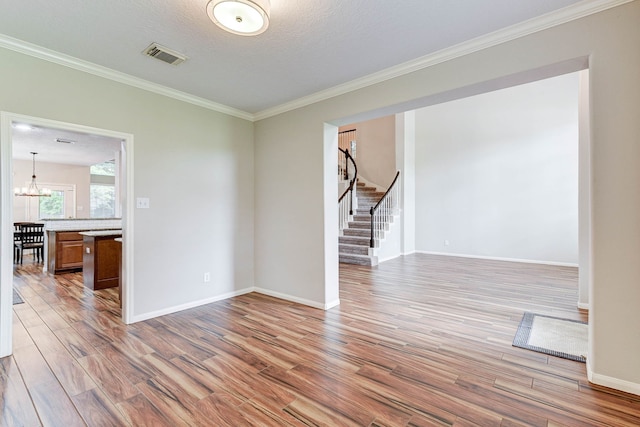 unfurnished room with a textured ceiling, light hardwood / wood-style flooring, an inviting chandelier, and ornamental molding