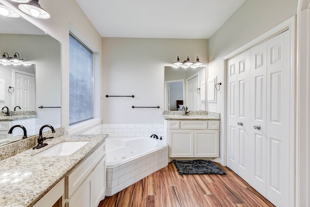 bathroom with vanity, hardwood / wood-style flooring, and tiled tub