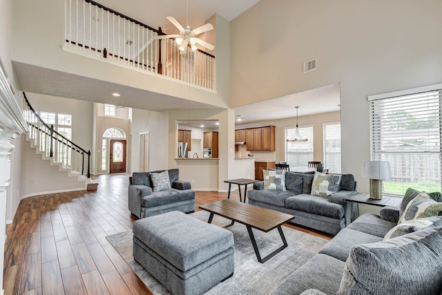 living room featuring light hardwood / wood-style flooring, a high ceiling, and ceiling fan