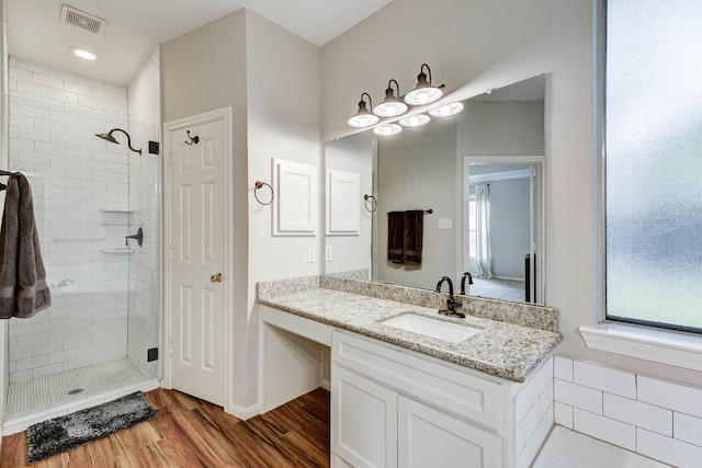 bathroom featuring vanity, hardwood / wood-style flooring, and a tile shower