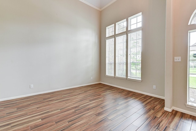 unfurnished room featuring wood-type flooring, a wealth of natural light, and ornamental molding