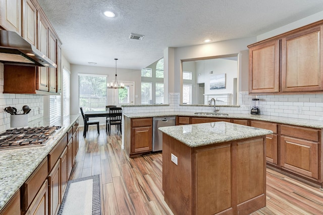 kitchen featuring hanging light fixtures, a textured ceiling, stainless steel appliances, sink, and a center island