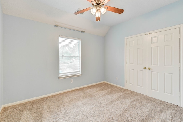 unfurnished bedroom featuring a closet, ceiling fan, vaulted ceiling, and carpet floors