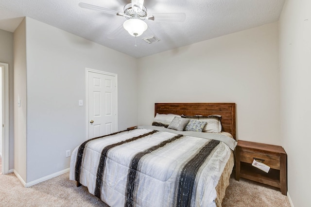 bedroom with a textured ceiling, light colored carpet, and ceiling fan