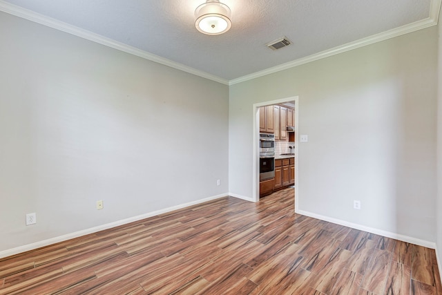 spare room with light hardwood / wood-style flooring, a textured ceiling, and crown molding