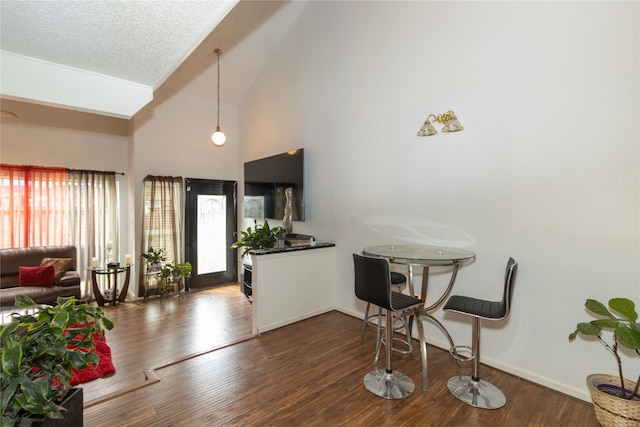 foyer with high vaulted ceiling, a healthy amount of sunlight, a textured ceiling, and dark hardwood / wood-style flooring