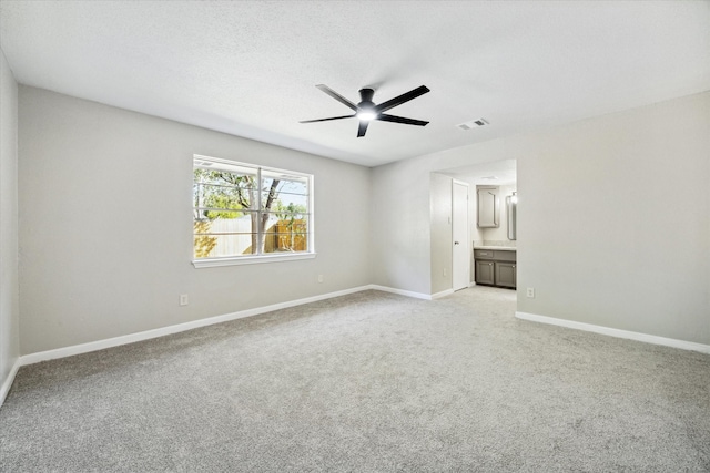 carpeted spare room with a textured ceiling and ceiling fan