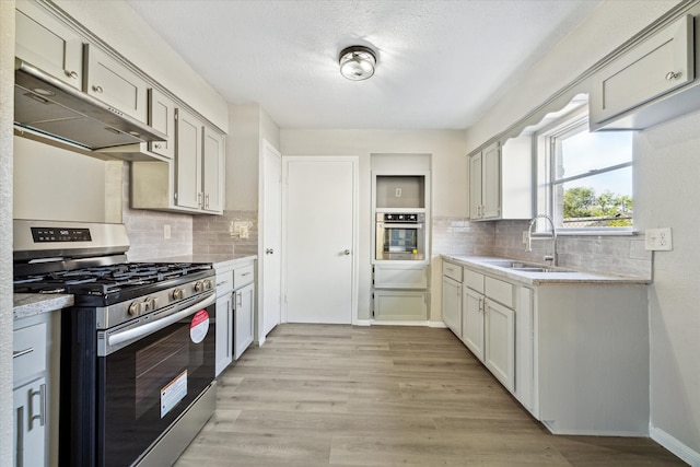 kitchen featuring light hardwood / wood-style floors, tasteful backsplash, stainless steel appliances, and sink