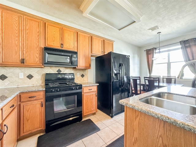 kitchen featuring hanging light fixtures, sink, black appliances, light tile patterned flooring, and a textured ceiling