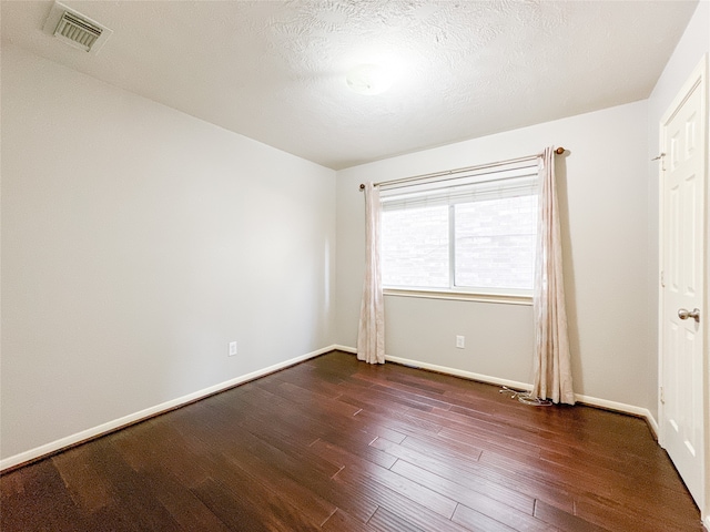 unfurnished room featuring a textured ceiling and dark hardwood / wood-style flooring