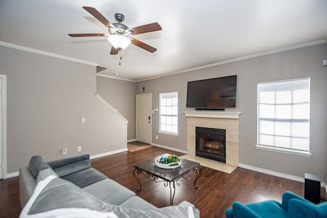 living room with ornamental molding, dark wood-type flooring, a tile fireplace, and ceiling fan