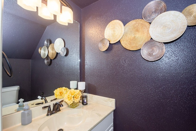 bathroom featuring vanity, vaulted ceiling, and toilet