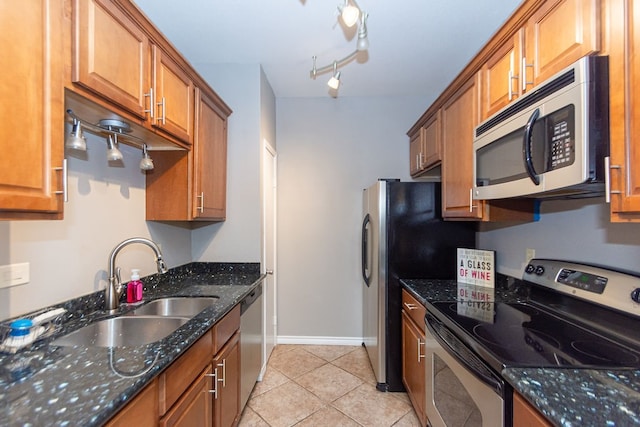 kitchen featuring stainless steel appliances, sink, dark stone counters, and light tile patterned floors