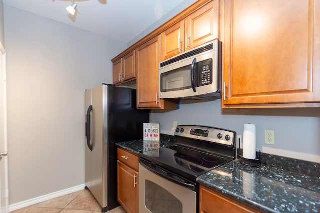 kitchen featuring appliances with stainless steel finishes, dark stone counters, and light tile patterned floors