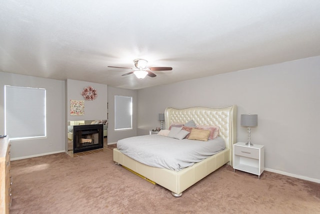 bedroom featuring ceiling fan, carpet flooring, and a tile fireplace