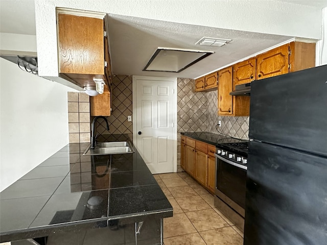 kitchen featuring backsplash, black refrigerator, sink, high end stainless steel range, and light tile patterned floors