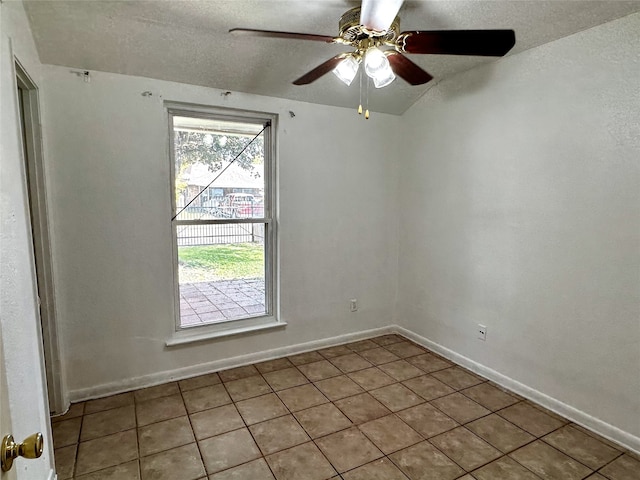 empty room with ceiling fan, light tile patterned flooring, and a textured ceiling