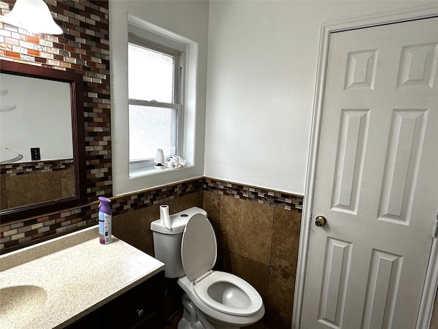 bathroom featuring vanity, tile walls, and toilet