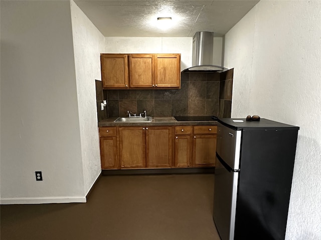 kitchen with stainless steel fridge, backsplash, black electric cooktop, sink, and wall chimney range hood