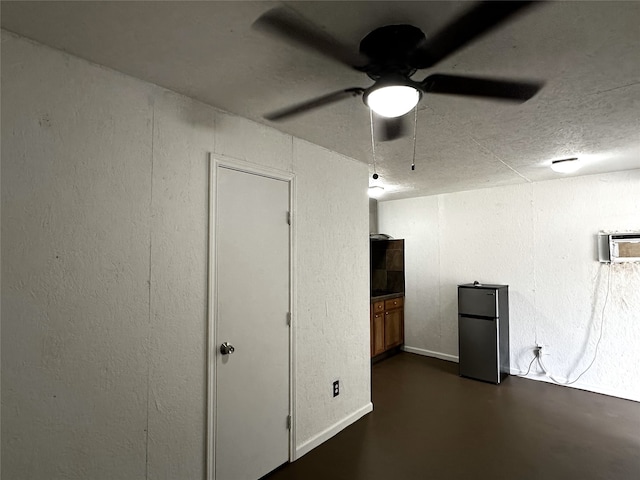 basement with an AC wall unit, stainless steel refrigerator, and ceiling fan