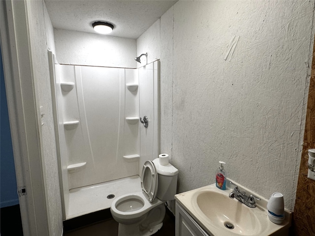 bathroom featuring toilet, vanity, a textured ceiling, and walk in shower