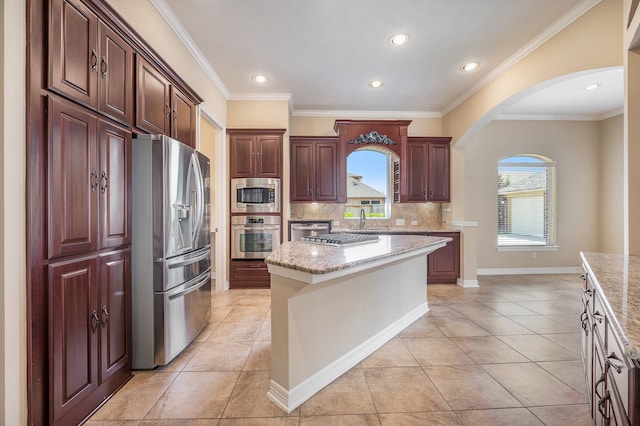 kitchen featuring a kitchen island, decorative backsplash, appliances with stainless steel finishes, and a healthy amount of sunlight