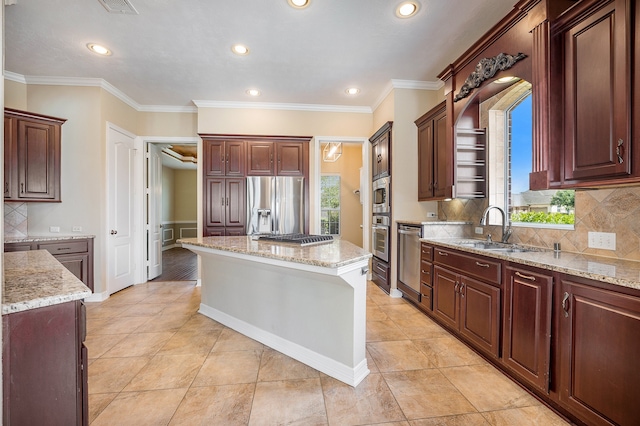 kitchen with tasteful backsplash, light stone counters, a kitchen island, sink, and stainless steel appliances