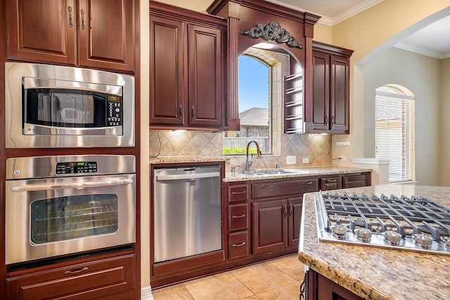 kitchen with appliances with stainless steel finishes, light stone counters, sink, and backsplash