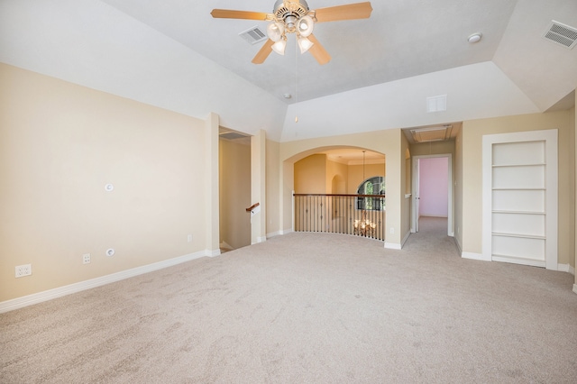 carpeted empty room with ceiling fan, vaulted ceiling, and built in shelves