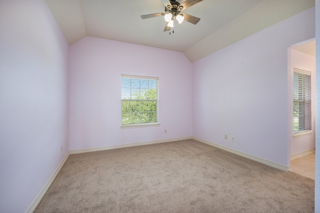 empty room featuring vaulted ceiling, light carpet, and ceiling fan