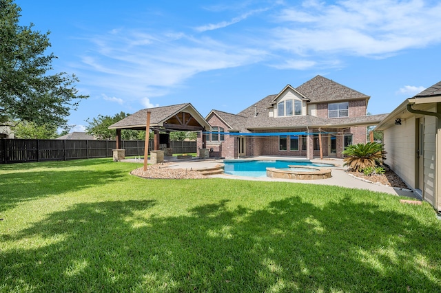 rear view of property featuring a gazebo, a pool with hot tub, a patio, and a yard