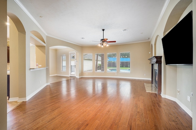 unfurnished living room featuring ceiling fan, wood-type flooring, ornamental molding, and a premium fireplace