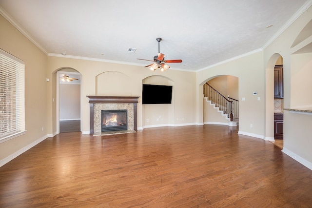 unfurnished living room with ornamental molding, a high end fireplace, hardwood / wood-style flooring, and ceiling fan