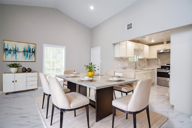 dining space featuring high vaulted ceiling and sink