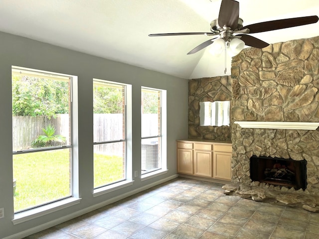 unfurnished living room with a stone fireplace, a healthy amount of sunlight, and lofted ceiling