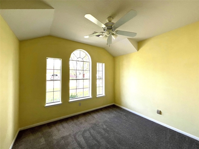 empty room featuring dark colored carpet, vaulted ceiling, and ceiling fan