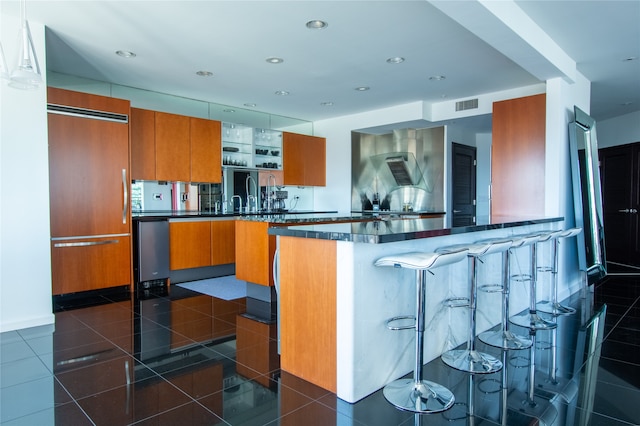 kitchen with dark tile patterned floors, stainless steel fridge, kitchen peninsula, and a breakfast bar area