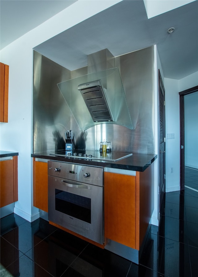 kitchen with dark tile patterned flooring, backsplash, extractor fan, and oven